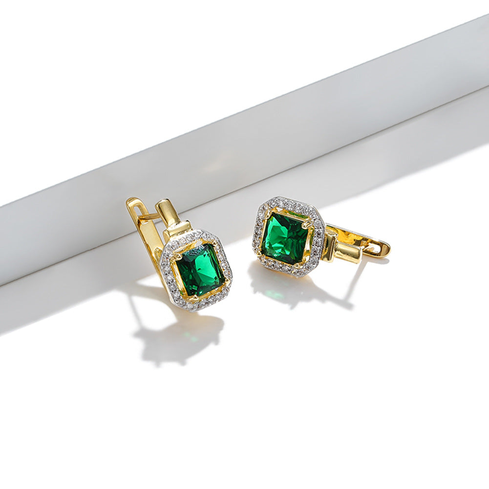 Gold earrings with green gemstones on a white background